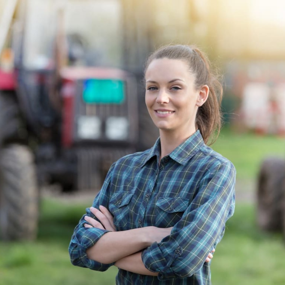 Femme agricultrice souriante devant un tracteur, illustrant la campagne social media de La Récolte.fr