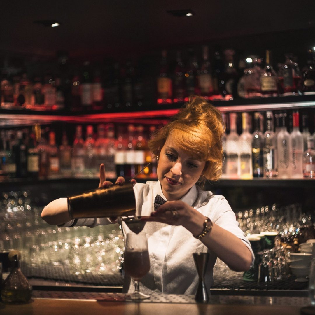 Barmaid professionnelle préparant un cocktail dans un bar, représentant l’Association des Barmen de France